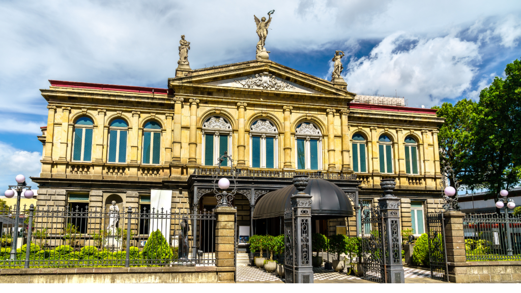 Ornate stone building with multiple arched windows, statues on the roof, a gated entrance, and manicured greenery—this landmark is one of the best places to visit in Costa Rica for architecture lovers.